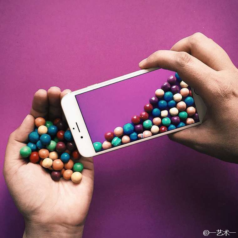 Une main tend des billes colorées qui semblent se déverser dans l'écran d'un téléphone
